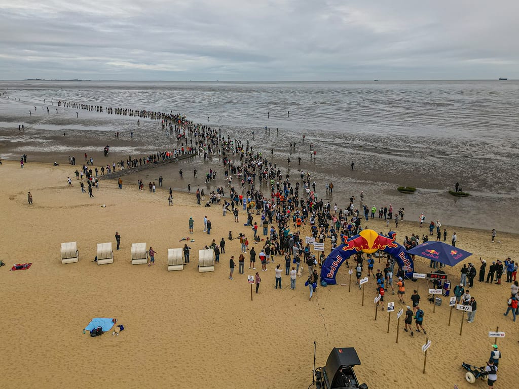 Zuschauer am Sahlenburger Strand beobachten den Wattlauf im geöffneten Wattenmeer bei Ebbe.
