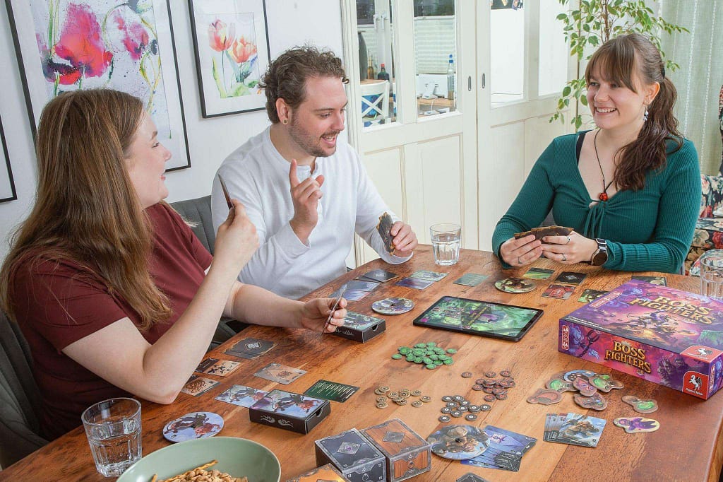 Spielrunde mit Boss Fighters QR am Tisch – Spieler nutzen Karten, Tablet und Spielmaterial während einer gemeinsamen Partie.